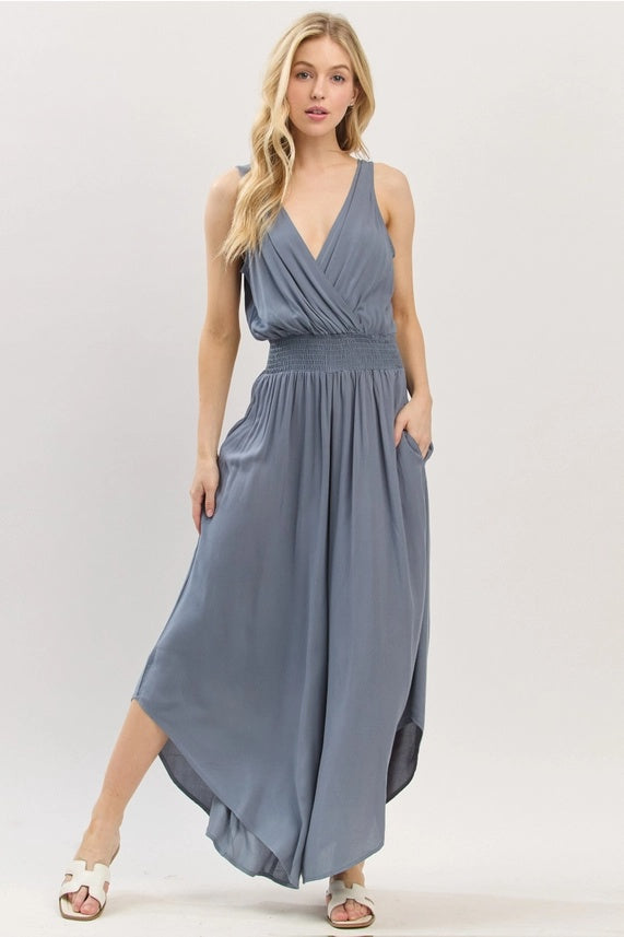 Woman wearing a sleeveless blue Smock Waist Jumpsuit on a white background